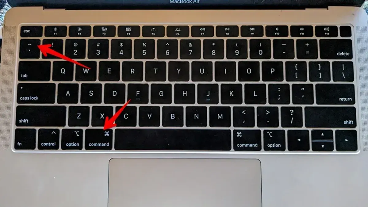 Person using Mac keyboard shortcut to switch between windows of the same app on a laptop