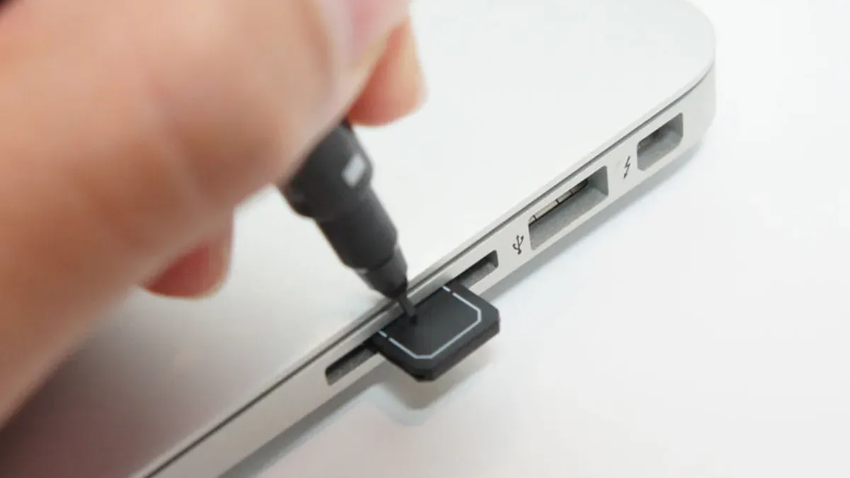 MacBook Air M5 with USB-C adapter connecting an SD card for photo transfer