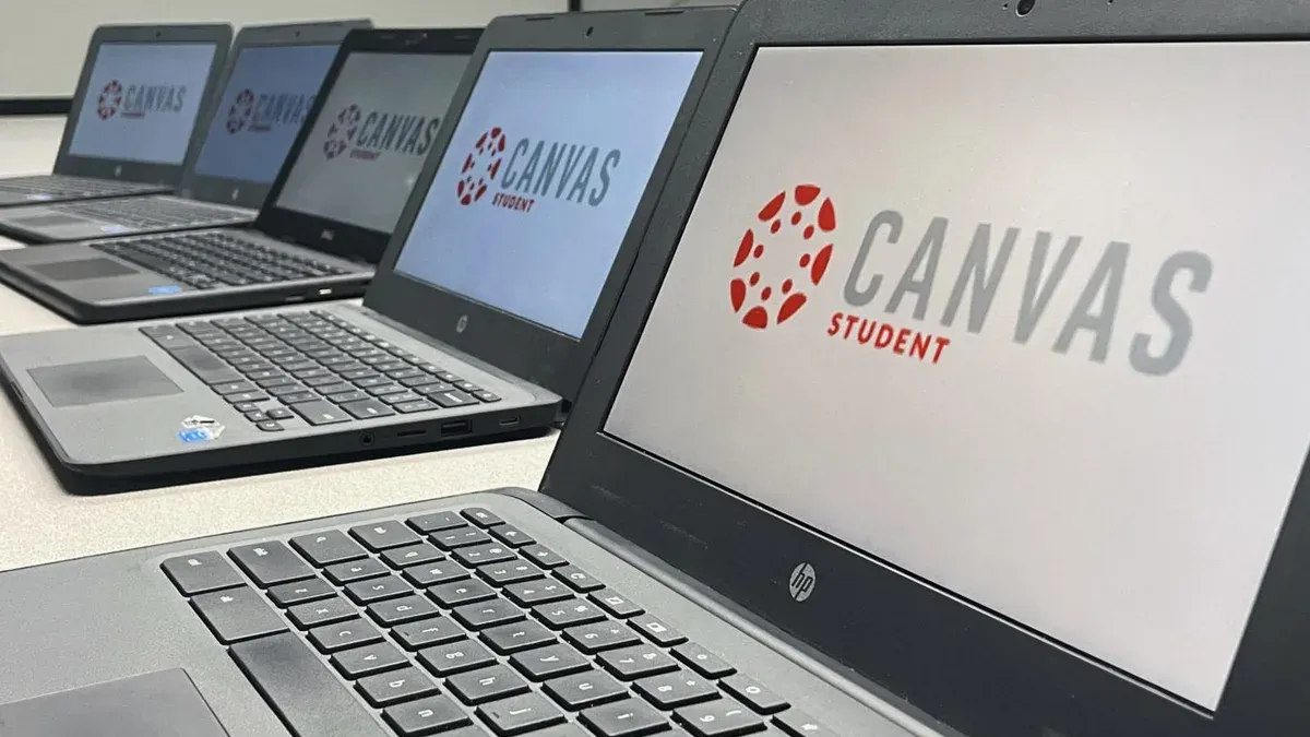 Teacher helping students with switching from Google Classroom to Canvas on laptops