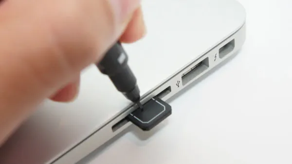 MacBook Air M5 with USB-C adapter connecting an SD card for photo transfer